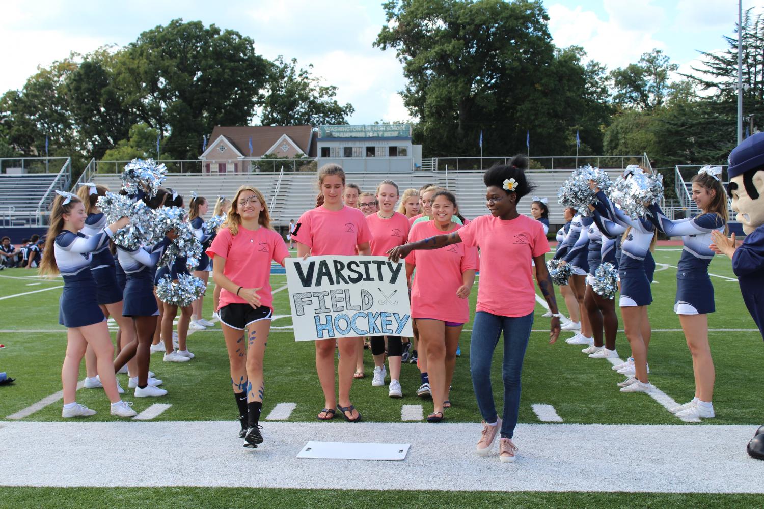 The varsity field hockey team is cheered on by the cheerleaders and the crowd at the pep rally