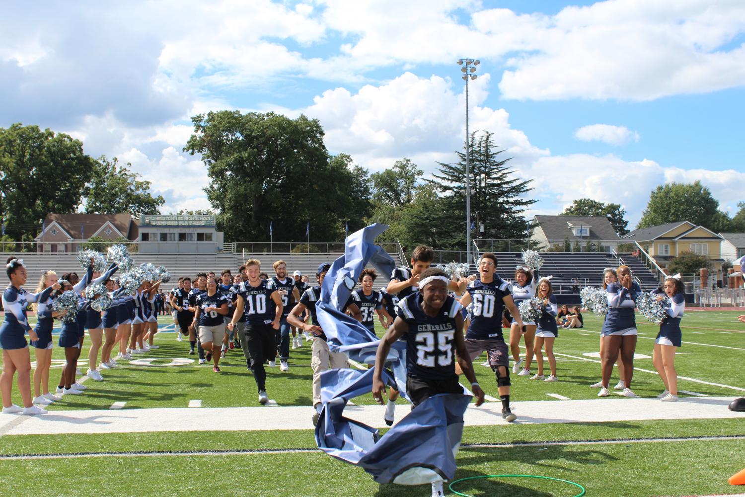 Cheerleaders and the crowd welcome the varsity football team as they rush the field