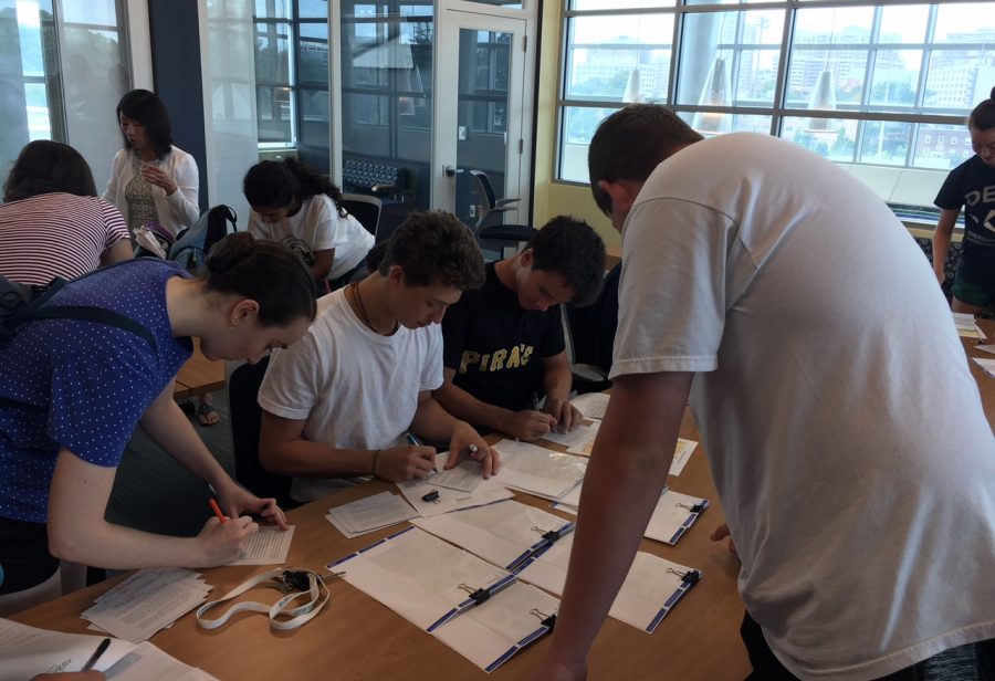 Juniors Julia Timpane and Angelo Lepore and senior Matthew Hopper sign postcards for the incoming freshmen. Every year the mentors mail out a card with a short letter about the Connect Mentors Program for each freshman.