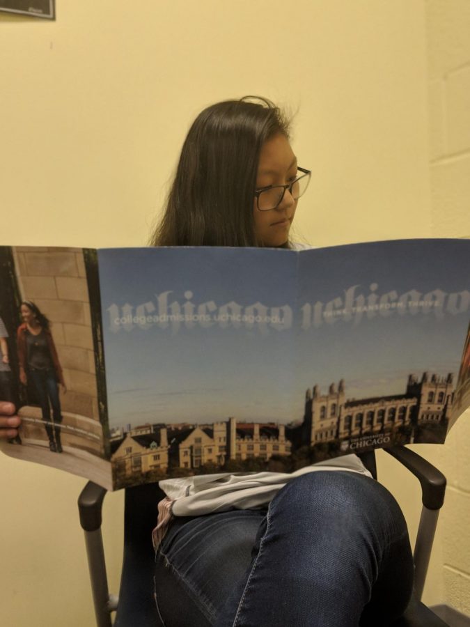 Sophomore Paige Dillon reads the University of Chicago’s pamphlet. Visiting colleges often provide information in these pamphlets, such as financial aid programs and graduation rates. 
