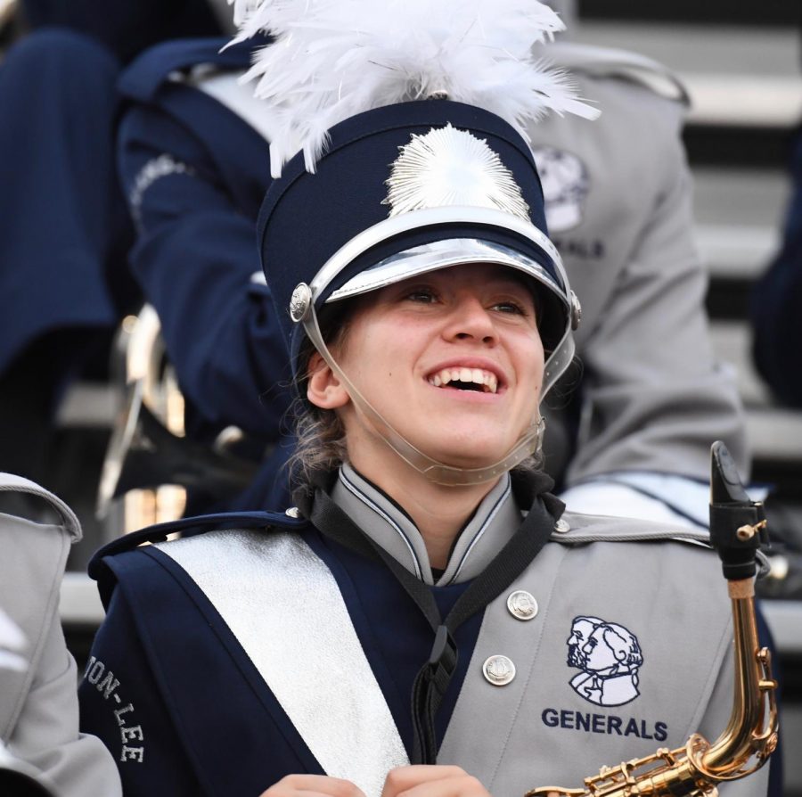 Senior+CeCe+Collinson+smiles+at+the+camera+while+sitting+in+the+stands+with+the+rest+of+the+marching+band.