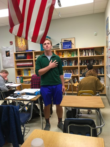 Senior Owen Potts stands for Pledge of Allegiance at the beginning of their busy day. As staying seated for the pledge has become a popular form of protest, some have been offended by students’ choices not to stand.