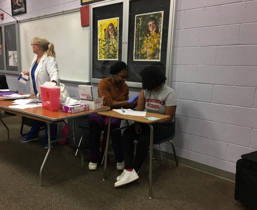 Junior Kalki Ausink receiving her annual flu shot from Medical Advisor Ms. Dorothy Cyphers, while other Medical Advisor Ms. Diane Lekang prepares for the next student. 