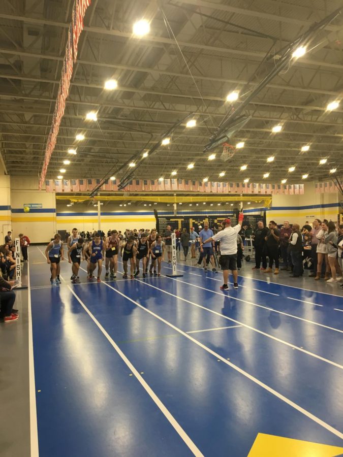 Varsity boys get ready to run the 1600 meter run finals. The boys bend their knees getting ready to run, waiting for the starter to shoot the starting pistol, which marks the start of the race.
