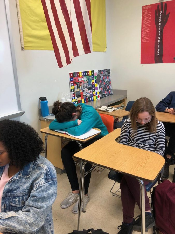 A student sits in the back of a crowded classroom. 