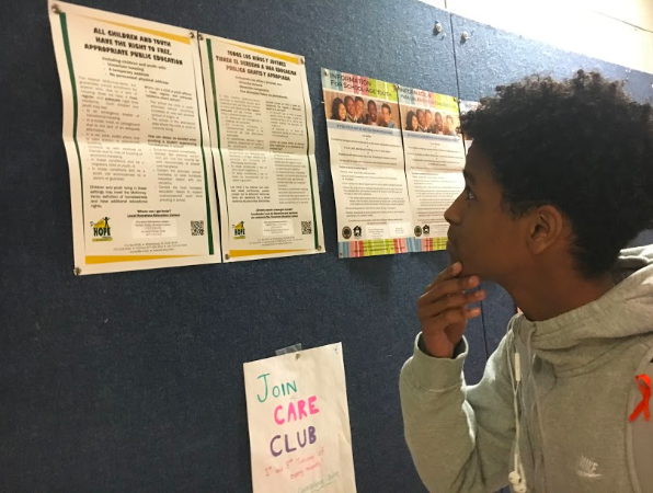 Junior Yonatan Belihu looking at public education posters in the main stairway. He is still deciding on whether or not he wants to go to a four-year college or pursue other options.