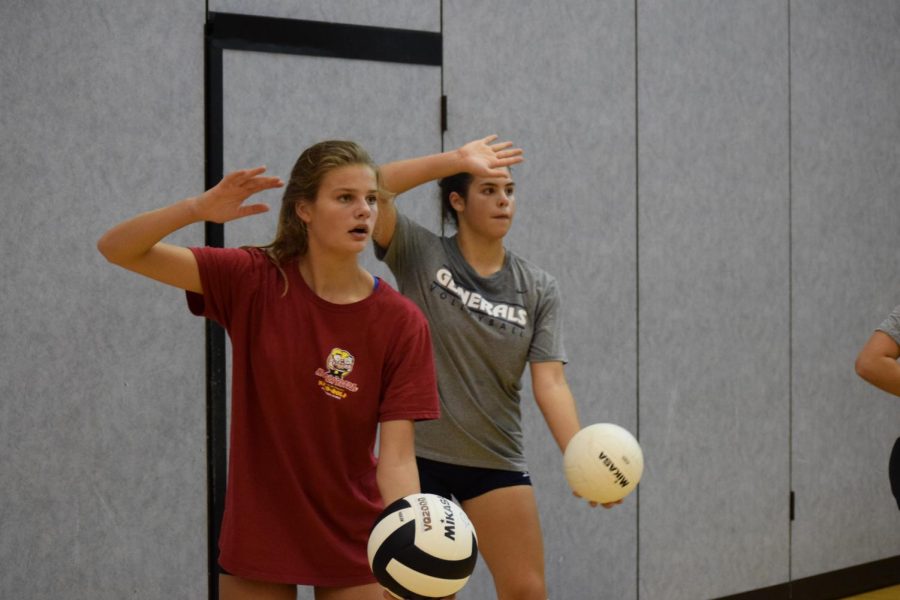 Freshman Tess Muldowney and Kaitlyn Cooper practice their serves. To complete the exercise, the team had to make fifty serves over the net. 