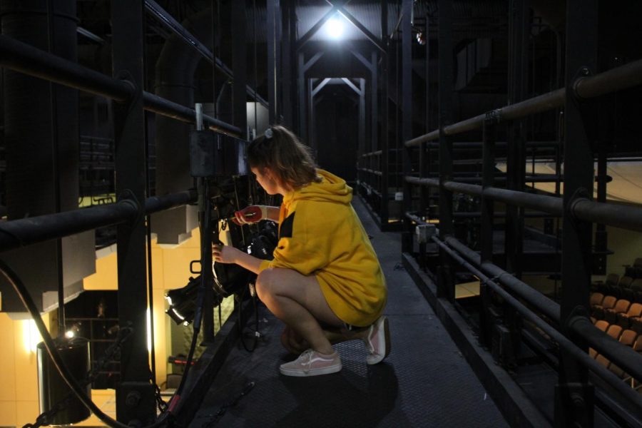 Senior Sarah Shaw works on the lights along the catwalk during a rehearsal. Shaw is the head of the lights department. 