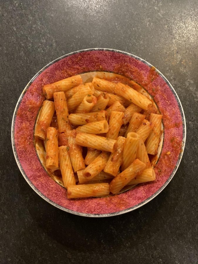 Microwaved pasta with marinara sauce is placed in a bowl and ready to eat. Cooking pasta in the microwave is much faster than waiting for water to boil.