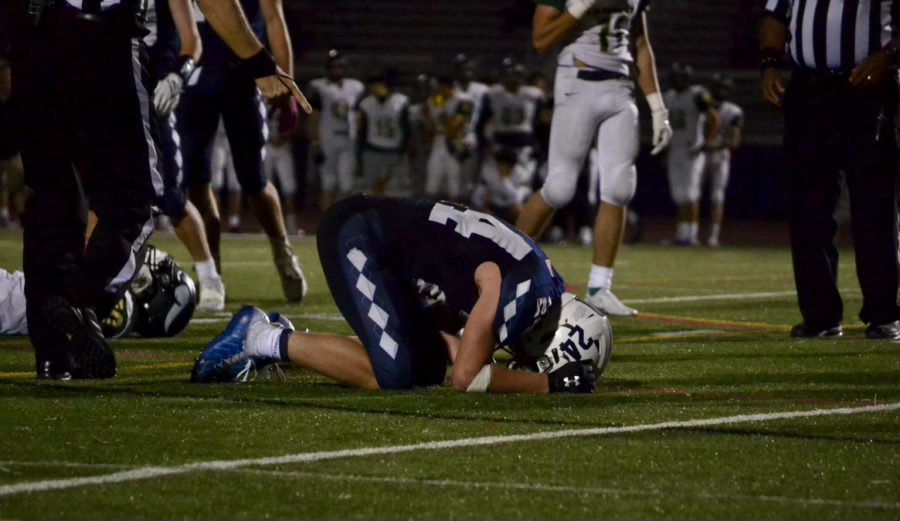 Junior Jackson Broadwell kneels over in pain after a collision with a Langley player, who lies behind him
