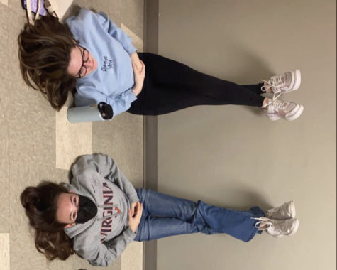 Juniors Yarden Footlik and Ilana Newton sit with their legs against the wall to reallocate blood. Footlik’s POTS caused her to lose blood flow to her brain, Newton, a friend, sits with her in the hallway while she works on her circulation.