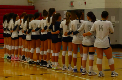The volleyball team had a good record this season. They stand together during the national anthem before a game.